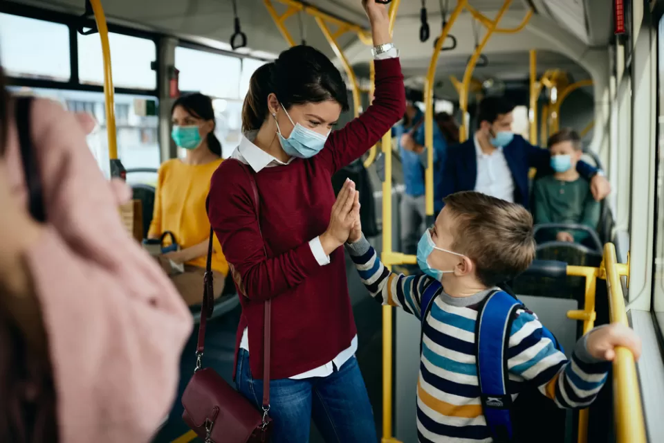 Smiling mother and child on busy public bus wearing Covid-19 protective masks